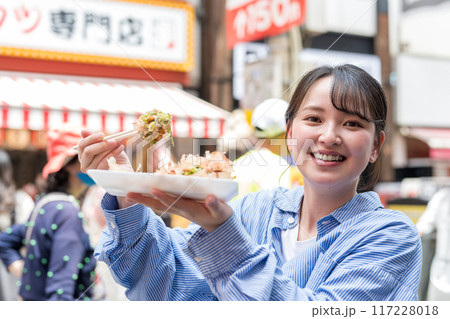 明るい屋外でたこ焼きを食べる女性|大阪府大阪市道頓堀にて 明るい屋外でたこ焼きを食べる女性|大阪府大阪市道頓堀にて 117228018