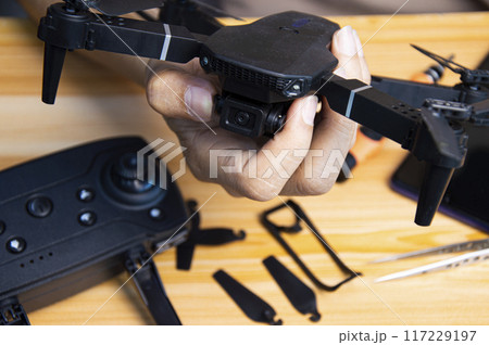 Professional mechanic repairing a drone on the table with various tools in modern workshop Professional mechanic repairing a drone on the table with various tools in modern workshop 117229197