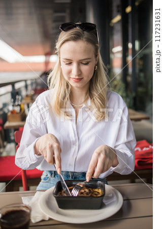 Blonde gen z woman eating lasagna in the cafe on break. Gen z girl spend time in restaurant Blonde gen z woman eating lasagna in the cafe on break. Gen z girl spend time in restaurant 117231631