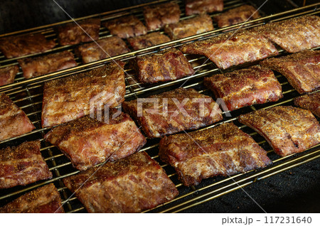 Grilled barbecue pork ribs in a smoker at the factory. The concept of a delicious snack for a picnic 117231640