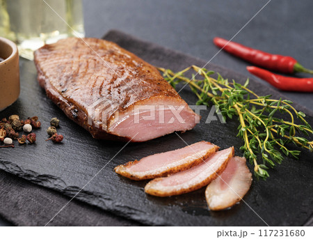 Grilled BBQ duck bacon in marinade and spices with sauce on a slate board with fresh herbs 117231680