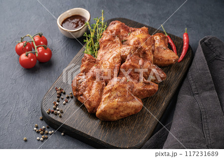 Grilled spicy chicken wings bbq  with sauce, tomato and fresh herb on a wooden board  117231689