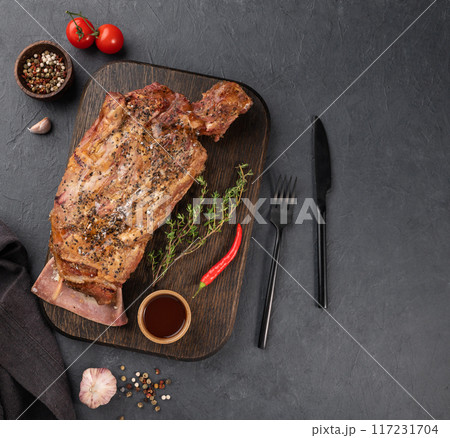 BBQ lamb shoulder cooked in a smoker with spices and sauce on a wooden board with fresh herbs BBQ lamb shoulder cooked in a smoker with spices and sauce on a wooden board with fresh herbs 117231704