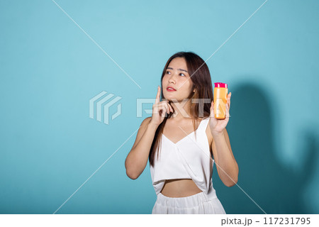 Beautiful Asian young woman holding body lotion on hand in studio shot isolated on blue background, Brunette female hold cream sunblock bottle, tube of sunscreen, Beauty cosmetics facial treatment Beautiful Asian young woman holding body lotion on hand in studio shot isolated on blue background, Brunette female hold cream sunblock bottle, tube of sunscreen, Beauty cosmetics facial treatment 117231795