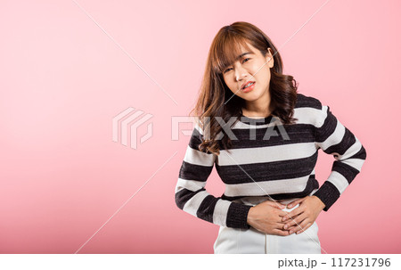 Portrait of Asian beautiful young woman has stomachache, female abdominal pain suffering from stomach ache, studio shot isolated on pink background, period pain, Health and medical gastritis concept 117231796