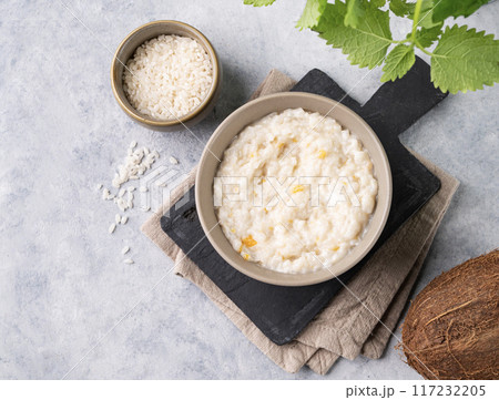 Rice porridge with fruit and coconut milk in bowl on a blue background. Concept healthy breakfast. Rice porridge with fruit and coconut milk in bowl on a blue background. Concept healthy breakfast. 117232205