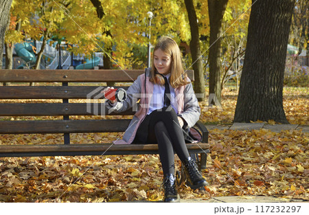 a girl sits on a bench in an autumn park a girl sits on a bench in an autumn park 117232297