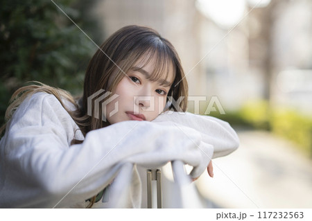 テラスの手すりにもたれかかる20代の女性　カメラ目線　ポートレート 117232563
