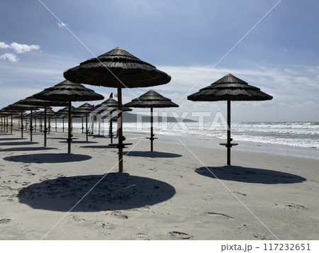 Sun parasol umbrellas on the beach in Porto Pino, Sardinia. Deserted empty beach with no people on a sunny day. Sun protection concept 117232651