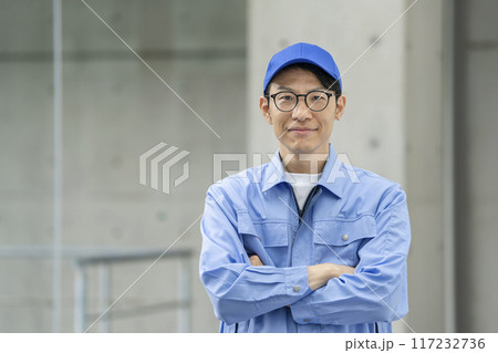 カメラ目線で腕組みをする作業服を着た30代の男性 117232736