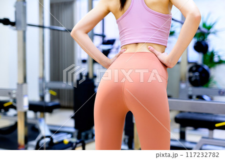 スポーツジムでポージングする後ろ姿の若い女性　ダイエット　ジム　筋トレ女子　美尻トレーニング 117232782