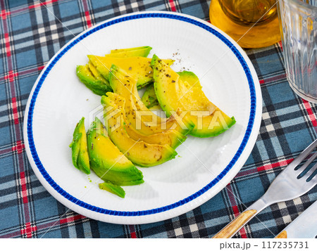 On table there is plate with snack - pieces of avocado pulp. On table there is plate with snack - pieces of avocado pulp. 117235731