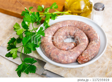 Raw Cumberland pork sausage with greens prepared for cooking 117235919