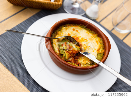 On wooden table traditional Italian dish is lasagna baked in oven under cheese crust. 117235962