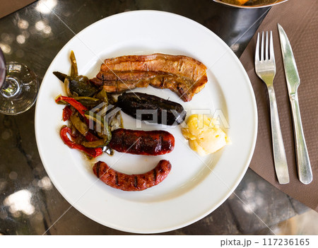 There is hearty appetizer of barbecue sausages and vegetables on plate. There is hearty appetizer of barbecue sausages and vegetables on plate. 117236165