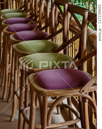 A row of chairs made of wood with cushions in purple and green colors 117236605