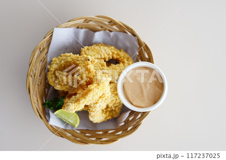 A close-up photo of a plate overflowing with golden fried calamari ring. 117237025