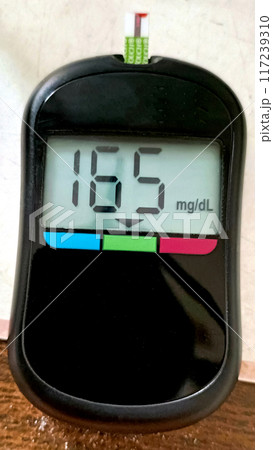 A close up of blood glucose meter with high sugar reading on wooden table 117239310