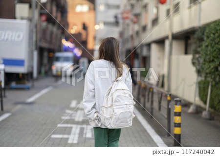 リュックを肩にかけて歩く若い女性　後ろ姿 117240042