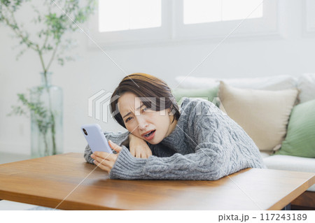 部屋でスマホを見る女性 117243189