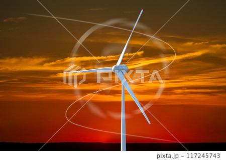 A wind turbine is spinning in the sky above a sunset A wind turbine is spinning in the sky above a sunset 117245743