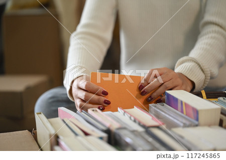 Close up image of young woman unpacking box with books in her new house Close up image of young woman unpacking box with books in her new house 117245865
