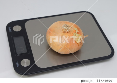 Golden flat onion on electronic kitchen scales. Proper nutrition. Calorie counting. Avitaminosis. Golden flat onion on electronic kitchen scales. Proper nutrition. Calorie counting. Avitaminosis. 117246591