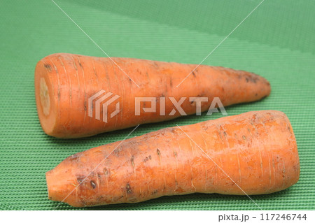 Poorly washed carrots lie on a green background, carrots deteriorate, proper nutrition. Poorly washed carrots lie on a green background, carrots deteriorate, proper nutrition. 117246744