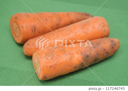 Poorly washed carrots lie on a green background, carrots deteriorate, proper nutrition. 117246745