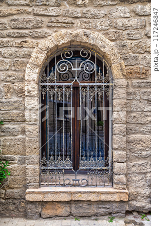 Decorative Iron Window With Stone Wall in Old Town at Dusk 117246847