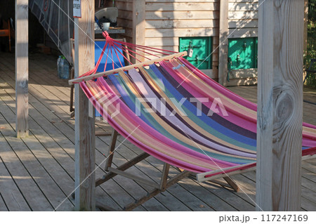 Hammock on wooden terrace of old barn near sea at beach. Nature and recreation. Meditation and relaxation. Background for text and design. Hammock on wooden terrace of old barn near sea at beach. Nature and recreation. Meditation and relaxation. Background for text and design. 117247169
