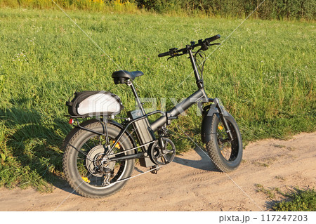 Electric folding bicycle for riding in nature in countryside. Sport and health. Summer hobby.  Electric folding bicycle for riding in nature in countryside. Sport and health. Summer hobby.  117247203
