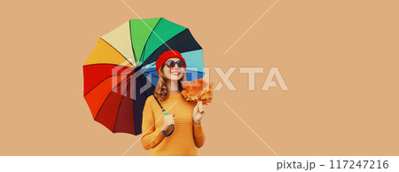 Autumn stylish cheerful young woman holds yellow maple leaves with colorful umbrella yellow sweater Autumn stylish cheerful young woman holds yellow maple leaves with colorful umbrella yellow sweater 117247216