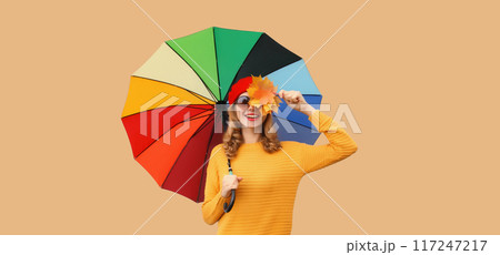 Autumn stylish cheerful young woman holds yellow maple leaves with colorful umbrella yellow sweater Autumn stylish cheerful young woman holds yellow maple leaves with colorful umbrella yellow sweater 117247217