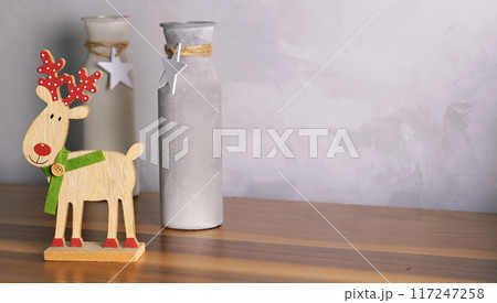 Decorative Christmas composition. Wooden reindeer and Christmas tree, vases with stars. Festive mood for living room. Template for postcard. Decorative Christmas composition. Wooden reindeer and Christmas tree, vases with stars. Festive mood for living room. Template for postcard. 117247258