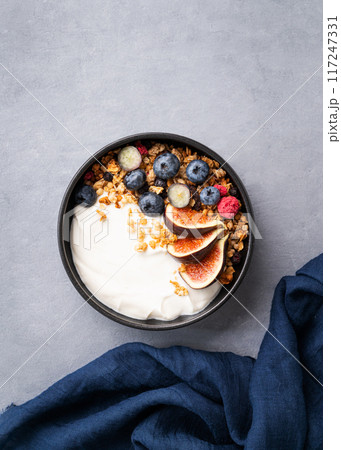 Delicious natural yogurt with granola and berries  in a bowl on a blue background.  117247331