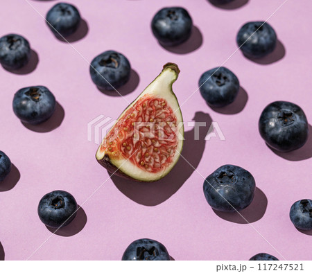 Layout of fresh blueberries and a slice of figs on a purple background close up. Layout of fresh blueberries and a slice of figs on a purple background close up. 117247521