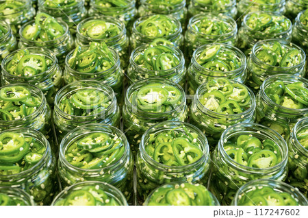 Fresh jalapeno peppers in jars close up. Preparation for conservation. Homemade canned vegetables. Fresh jalapeno peppers in jars close up. Preparation for conservation. Homemade canned vegetables. 117247602