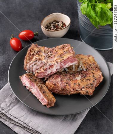Grilled bbq lamb ribs with tomato and fresh herb on a plate on a dark background close up. Grilled bbq lamb ribs with tomato and fresh herb on a plate on a dark background close up. 117247608