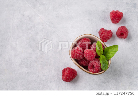 Juicy forest raspberry with mint leaf i a bowl on a light textured background. Healthy food concept 117247750