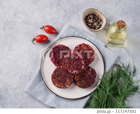 Fried vegetarian cutlets from beet, on a plate on a light background with fresh herbs and tomatoes. 117247881