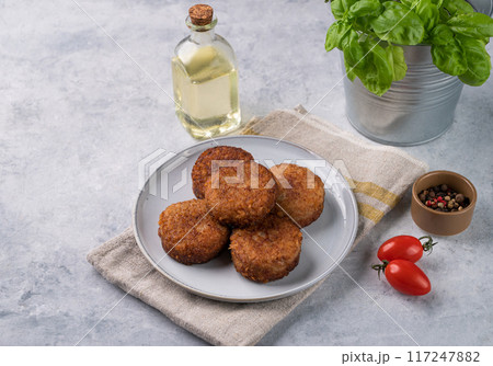 Chicken cutlets, fried, on a plate on a light background with fresh herbs, oil and tomatoes. Chicken cutlets, fried, on a plate on a light background with fresh herbs, oil and tomatoes. 117247882