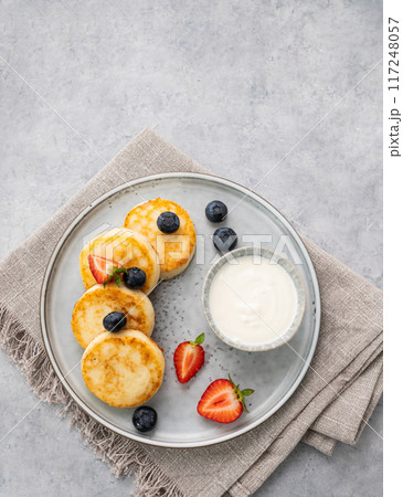 cheesecakes or  cottage cheese or syrniki with fresh blerries and sour cream on a gray background.  117248057