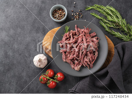 Traditional bbq torn  beef or lamb meat with spice, fresh tomatoes and herbs on a dark background. 117248434