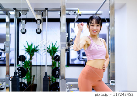 スポーツジムでポージングする笑顔の若い女性 ダイエット パーソナルジム 筋トレ女子 ガッツポーズ スポーツジムでポージングする笑顔の若い女性 ダイエット パーソナルジム 筋トレ女子 ガッツポーズ 117248452