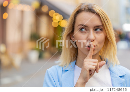 Woman lady presses index finger to lips makes silence hush gesture sign do not tells gossip secret Woman lady presses index finger to lips makes silence hush gesture sign do not tells gossip secret 117248656