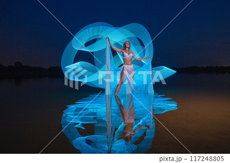 Young slim girl posing in water with abstract blue light effect Young slim girl posing in water with abstract blue light effect 117248805