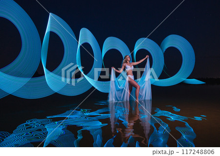 Young slim girl posing in water with abstract blue light effect Young slim girl posing in water with abstract blue light effect 117248806