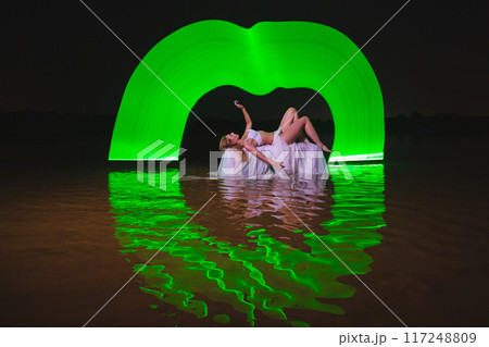 Young slim girl posing in water with abstract green light effect Young slim girl posing in water with abstract green light effect 117248809