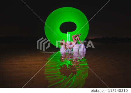 Young slim girl posing in water with abstract green light effect Young slim girl posing in water with abstract green light effect 117248810